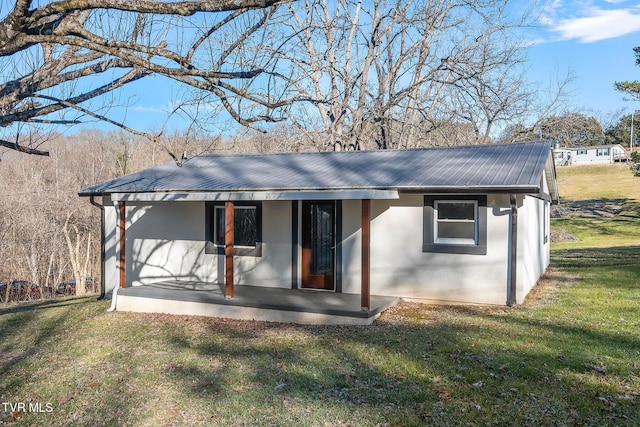 rear view of property featuring a lawn and a porch