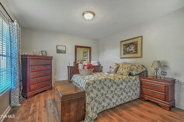 bedroom featuring dark hardwood / wood-style flooring and a textured ceiling