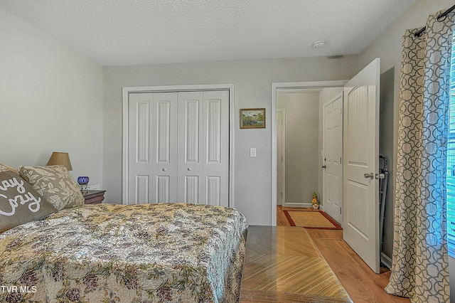 bedroom featuring a textured ceiling, light hardwood / wood-style flooring, and a closet