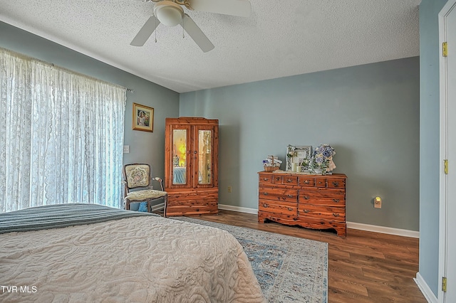 bedroom with ceiling fan, dark hardwood / wood-style flooring, and a textured ceiling