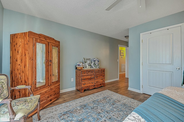 bedroom featuring ceiling fan, dark hardwood / wood-style floors, and a textured ceiling