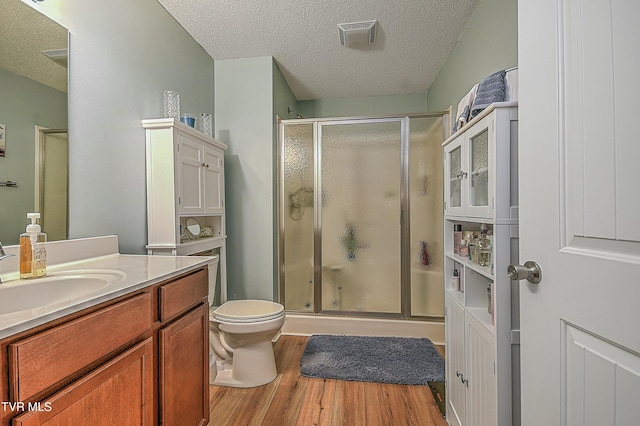 bathroom with hardwood / wood-style flooring, vanity, a shower with shower door, and a textured ceiling