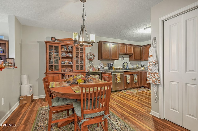 kitchen with sink, dishwasher, dark wood-type flooring, a notable chandelier, and a textured ceiling