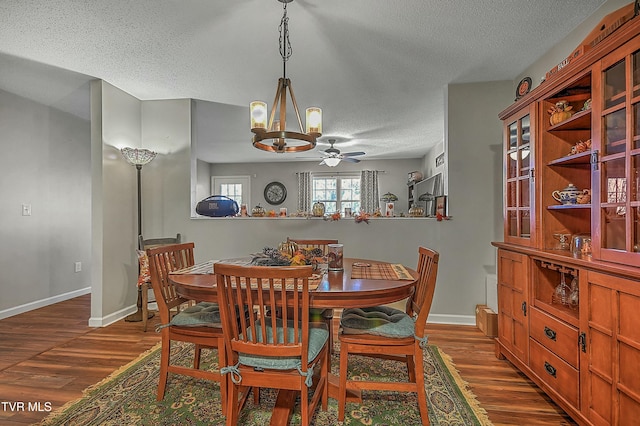 dining area featuring ceiling fan with notable chandelier, dark hardwood / wood-style flooring, and a textured ceiling