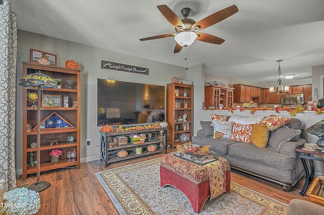 living room featuring ceiling fan, hardwood / wood-style floors, and a textured ceiling