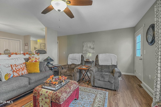 living room with ceiling fan, a textured ceiling, and light hardwood / wood-style flooring