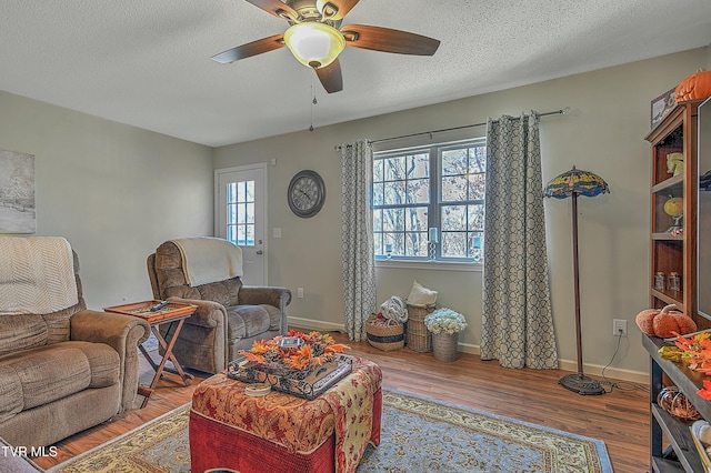 living room featuring hardwood / wood-style floors, ceiling fan, and a textured ceiling