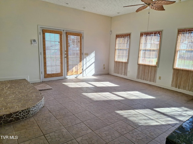 interior space with ceiling fan, a textured ceiling, and french doors