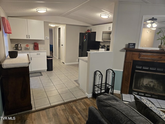 kitchen featuring lofted ceiling, black refrigerator with ice dispenser, white cabinets, light hardwood / wood-style flooring, and ceiling fan