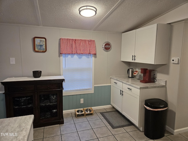 kitchen with light tile patterned floors, white cabinets, and a textured ceiling