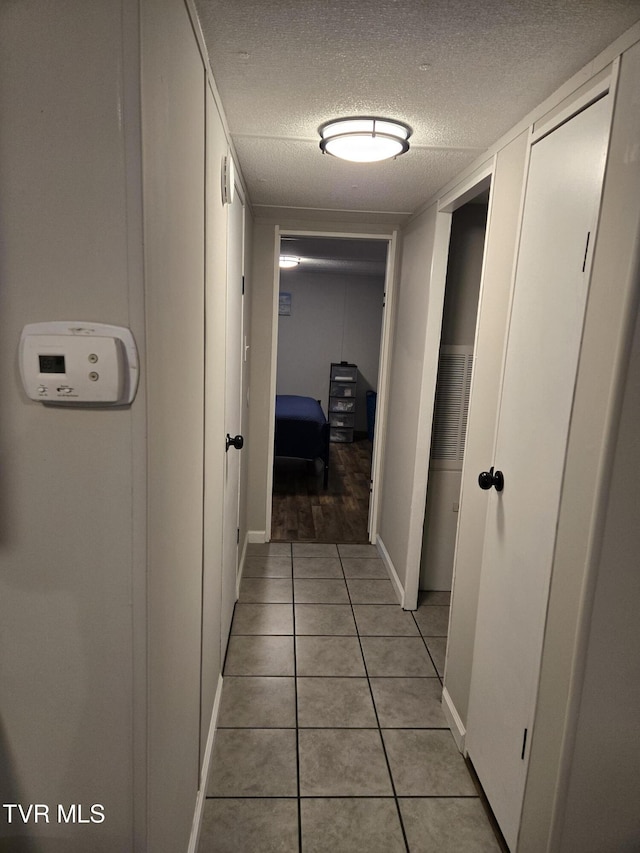 hallway with light tile patterned floors and a textured ceiling