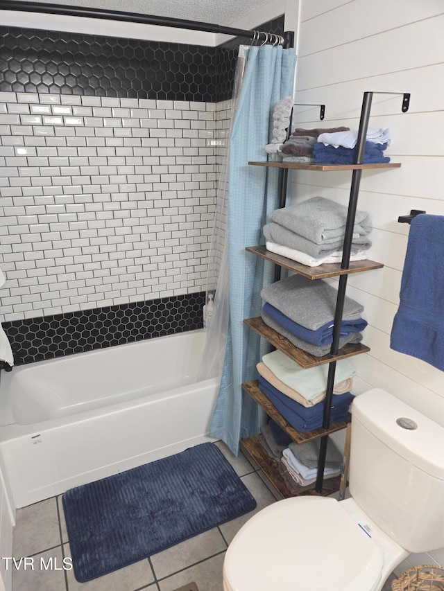 bathroom featuring tile patterned floors, wood walls, shower / tub combo, and toilet