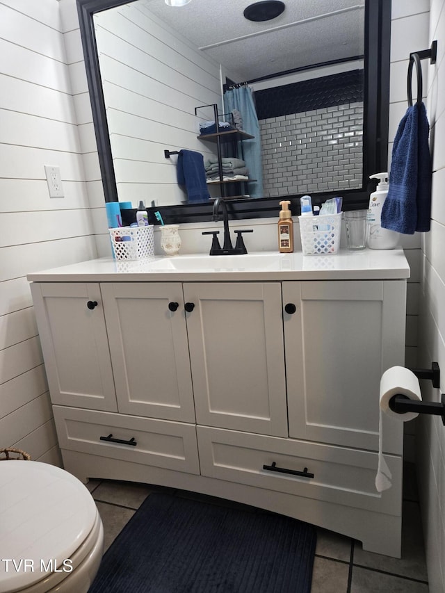 bathroom with tile patterned flooring, a textured ceiling, vanity, and toilet