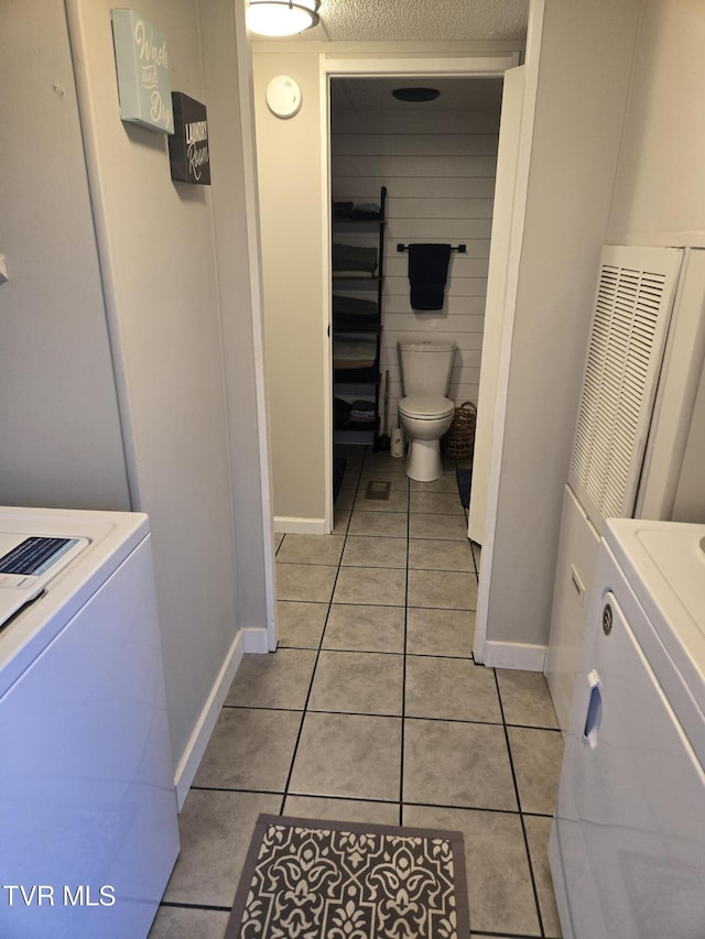 bathroom with toilet, tile patterned flooring, and washer / dryer