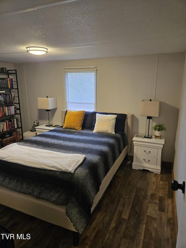 bedroom with a textured ceiling and dark hardwood / wood-style floors