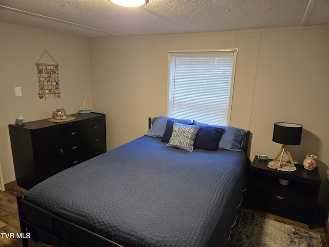 bedroom with dark hardwood / wood-style floors and a textured ceiling