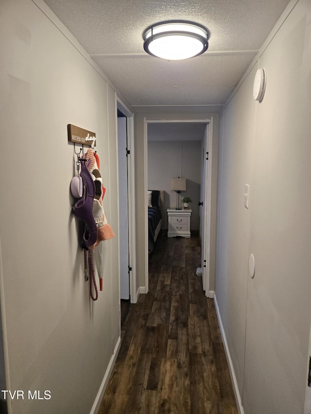 corridor featuring dark wood-type flooring and a textured ceiling