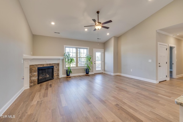 unfurnished living room with light hardwood / wood-style floors, a stone fireplace, and ceiling fan