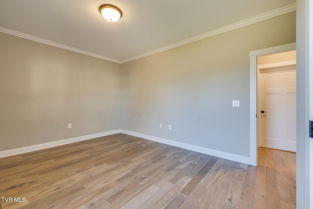 empty room featuring light wood-type flooring and crown molding