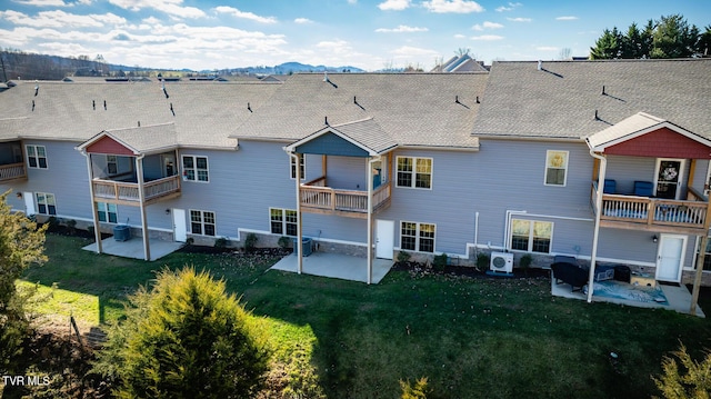 back of house featuring ac unit, a mountain view, a balcony, a yard, and a patio area