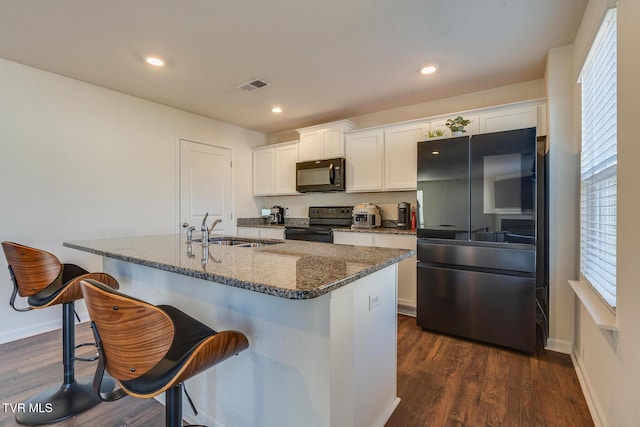 kitchen featuring a kitchen bar, dark hardwood / wood-style flooring, sink, black appliances, and white cabinets