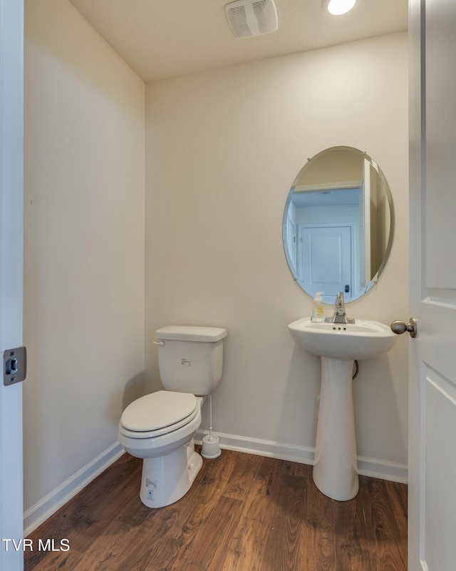 bathroom with hardwood / wood-style flooring and toilet