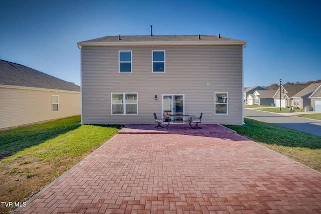 back of property with a lawn and a patio