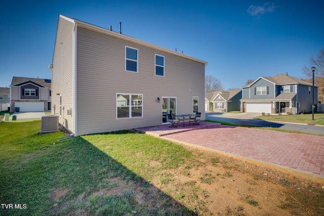 rear view of property with a lawn, cooling unit, a patio, and a garage