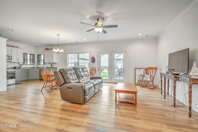 living room with crown molding, light hardwood / wood-style flooring, and ceiling fan with notable chandelier