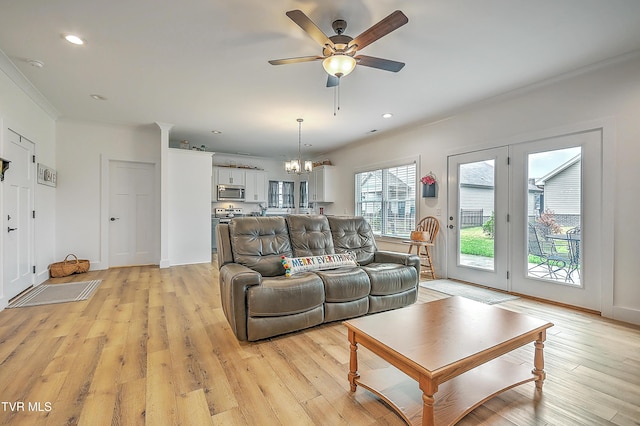 living room featuring crown molding, light hardwood / wood-style flooring, and ceiling fan with notable chandelier