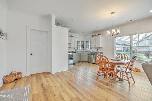 dining room featuring a chandelier, light wood-type flooring, and crown molding