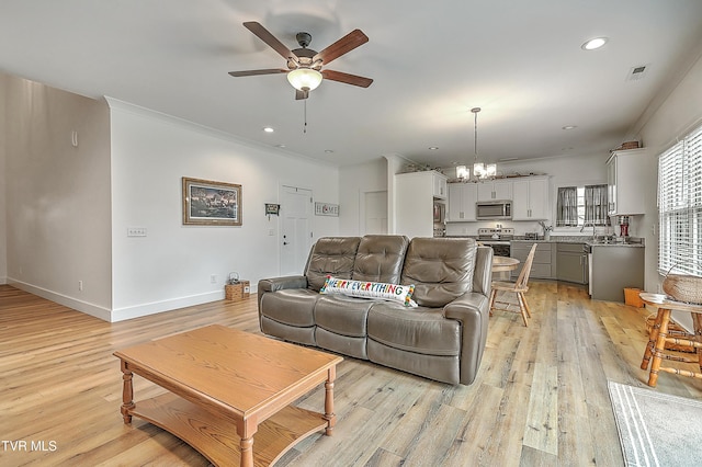 living room with light hardwood / wood-style floors, ceiling fan with notable chandelier, and ornamental molding