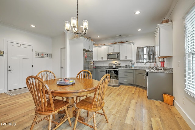 dining area with a wealth of natural light, light hardwood / wood-style flooring, a chandelier, and ornamental molding