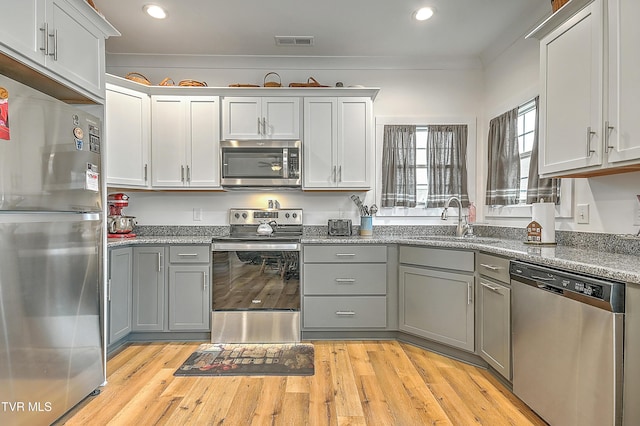 kitchen with gray cabinetry, light wood-type flooring, sink, and appliances with stainless steel finishes