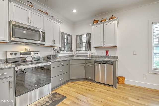 kitchen featuring sink, light wood-type flooring, stainless steel appliances, and a wealth of natural light