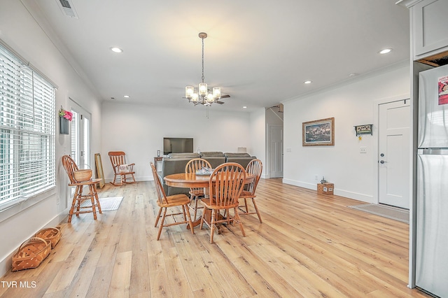 dining space with ornamental molding, light hardwood / wood-style floors, and a notable chandelier