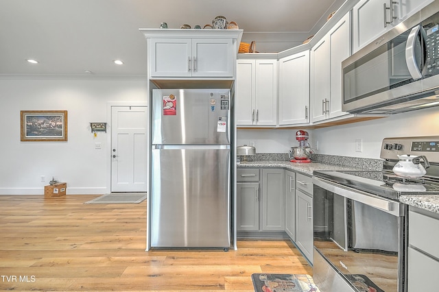 kitchen featuring light stone counters, crown molding, light hardwood / wood-style floors, and appliances with stainless steel finishes