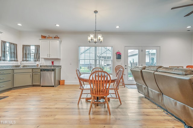 dining space featuring sink, ceiling fan with notable chandelier, and light wood-type flooring