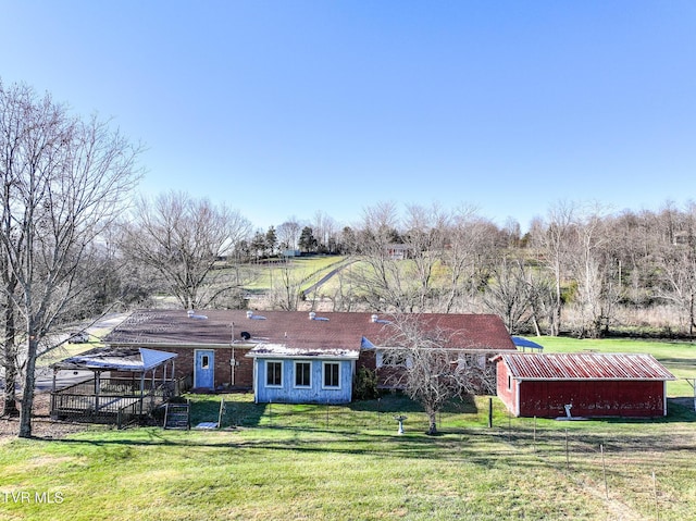 rear view of property featuring a yard, a rural view, and an outdoor structure