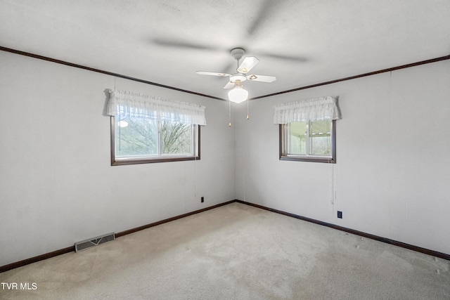 empty room with ceiling fan, ornamental molding, light carpet, and a wealth of natural light