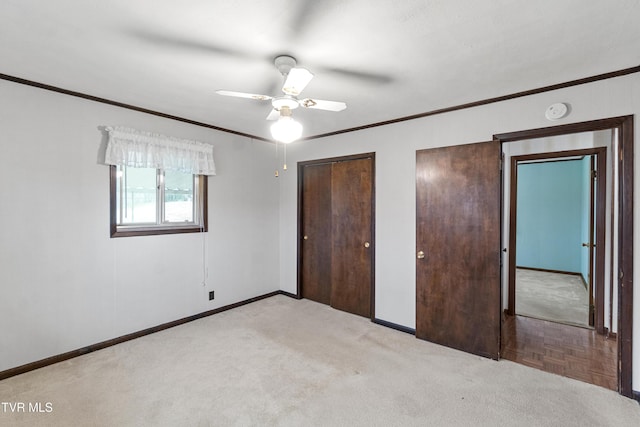 unfurnished bedroom featuring light carpet, two closets, ceiling fan, and crown molding