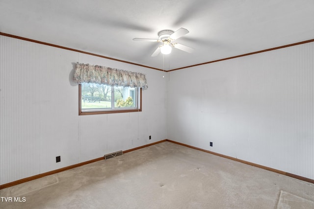 carpeted spare room with ceiling fan and ornamental molding