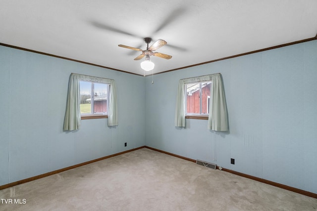 carpeted spare room with ceiling fan and crown molding