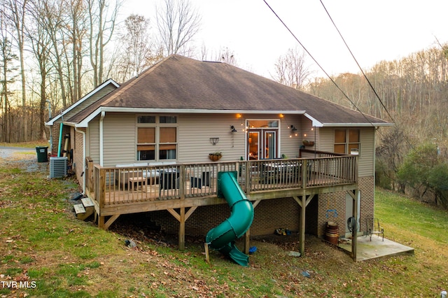 back of house featuring central air condition unit, a wooden deck, and a yard