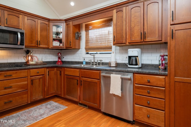 kitchen with light hardwood / wood-style floors, lofted ceiling, appliances with stainless steel finishes, and tasteful backsplash