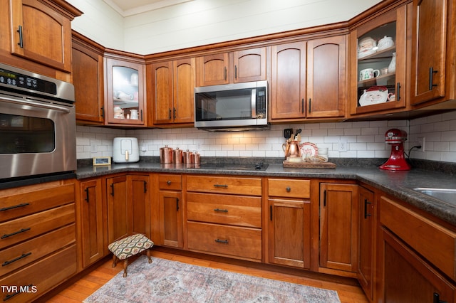 kitchen featuring light wood-type flooring, stainless steel appliances, and tasteful backsplash