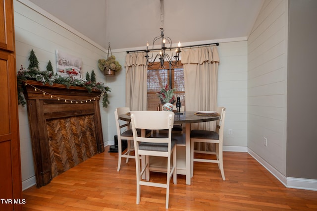 dining area with light hardwood / wood-style floors, vaulted ceiling, and an inviting chandelier