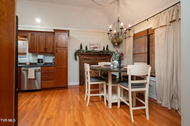 dining area with light hardwood / wood-style flooring, ornamental molding, vaulted ceiling, and an inviting chandelier