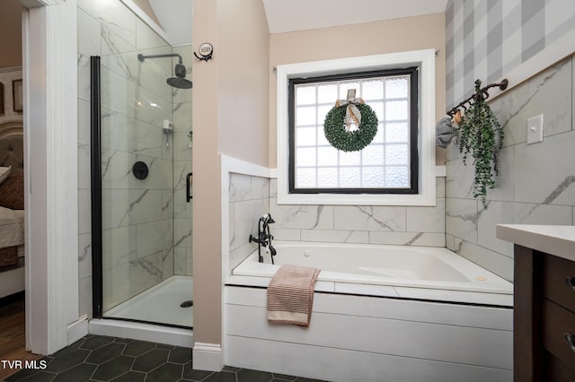 bathroom with tile patterned flooring, shower with separate bathtub, vanity, and tile walls