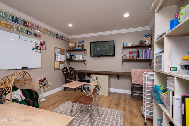 home office featuring built in desk, light hardwood / wood-style floors, and crown molding